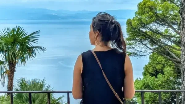 Lina creator of the mindful cozy living blog looking out at the ocean from a balcony, practicing slow living and mindfulness.